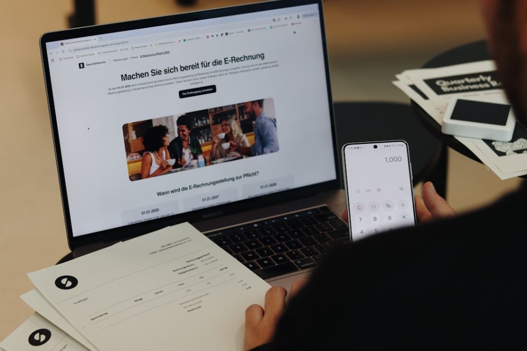 A man sitting in front of a laptop computer entrepreneur working on laptop, branding board, logo sketches, small business workspace