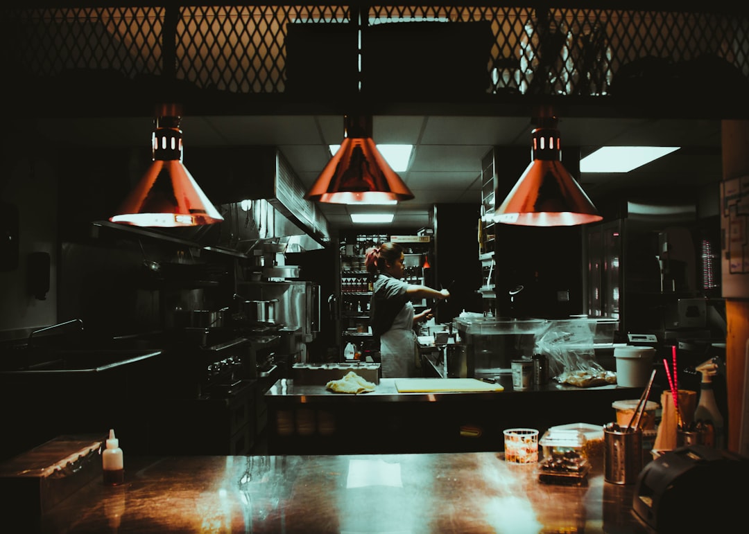 woman standing near three red pendant lamps kitchen display, restaurant orders, chefs, indian food