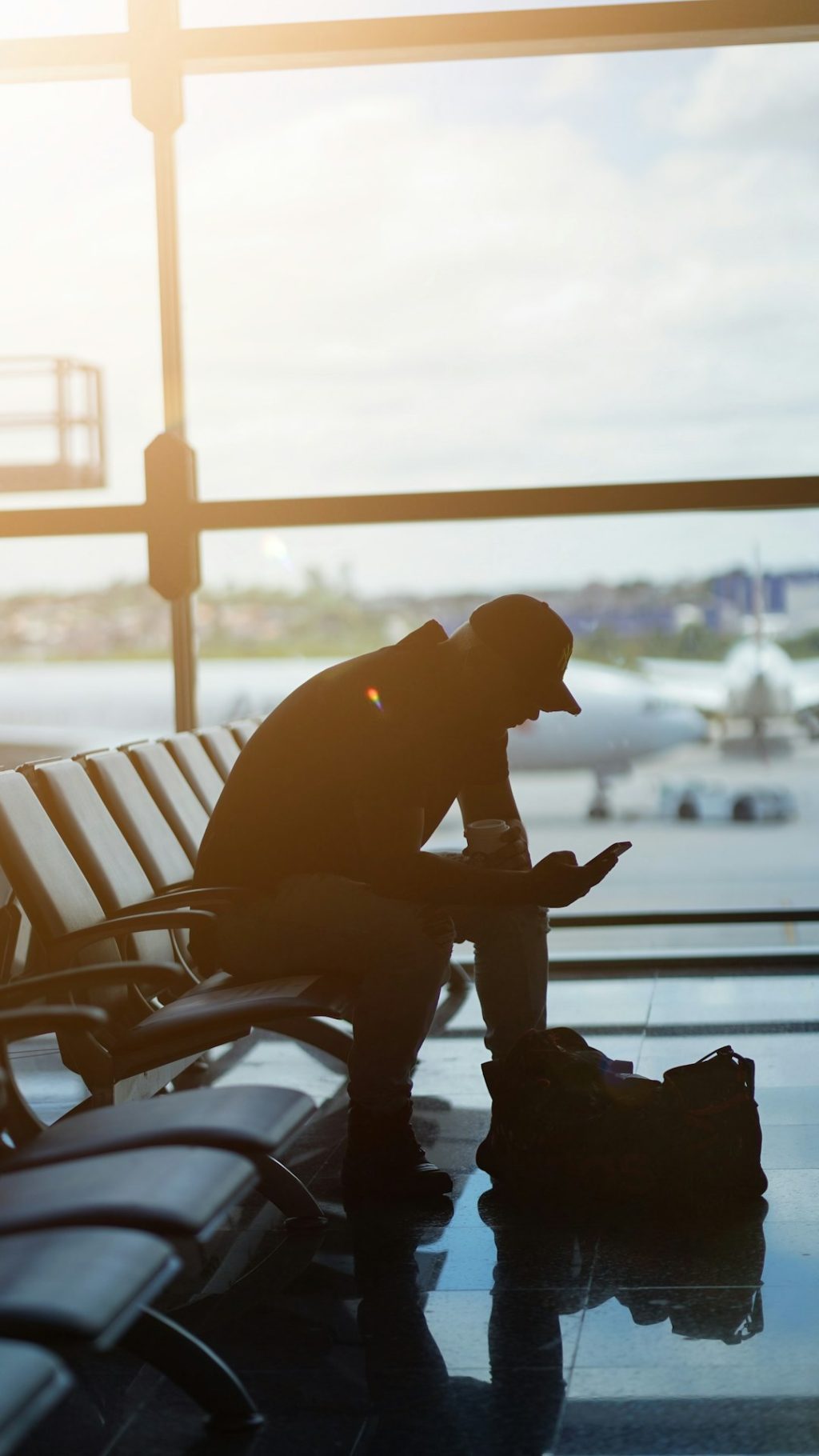 a man sitting at an airport looking at his cell phone smartphone esim setup screen travel airport