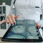 Doctor shows brain scan on tablet in office doctor using tablet, hospital data dashboard, artificial intelligence healthcare