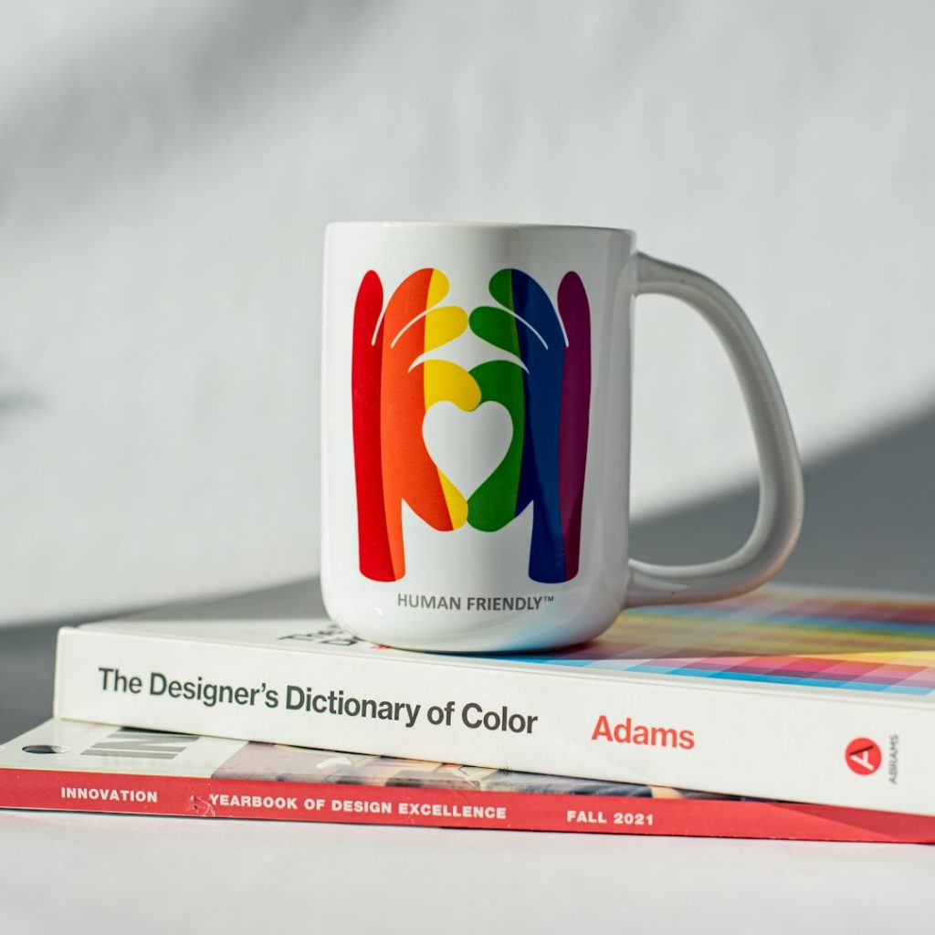 a coffee mug sitting on top of a stack of books branding workspace, logo design process, color palette samples