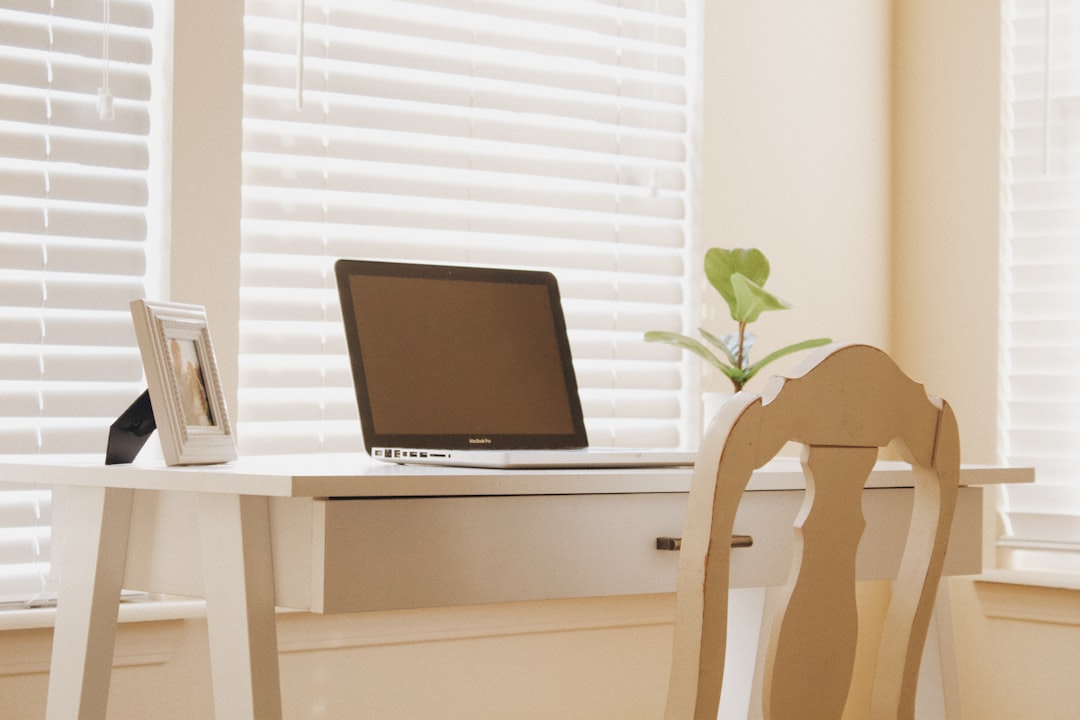 a laptop computer sitting on top of a wooden desk organized home office desk, tablet with inventory app, household items neatly arranged