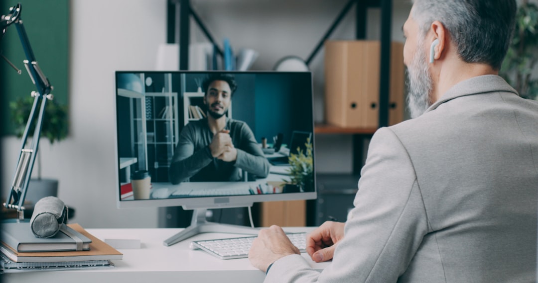A man sitting at a desk in front of a computer webinar host speaking, live chat reactions, virtual networking table