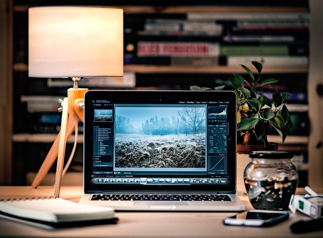 MacBook Pro on brown wooden table inside room photo editing workspace, background removal before and after, image editing software interface