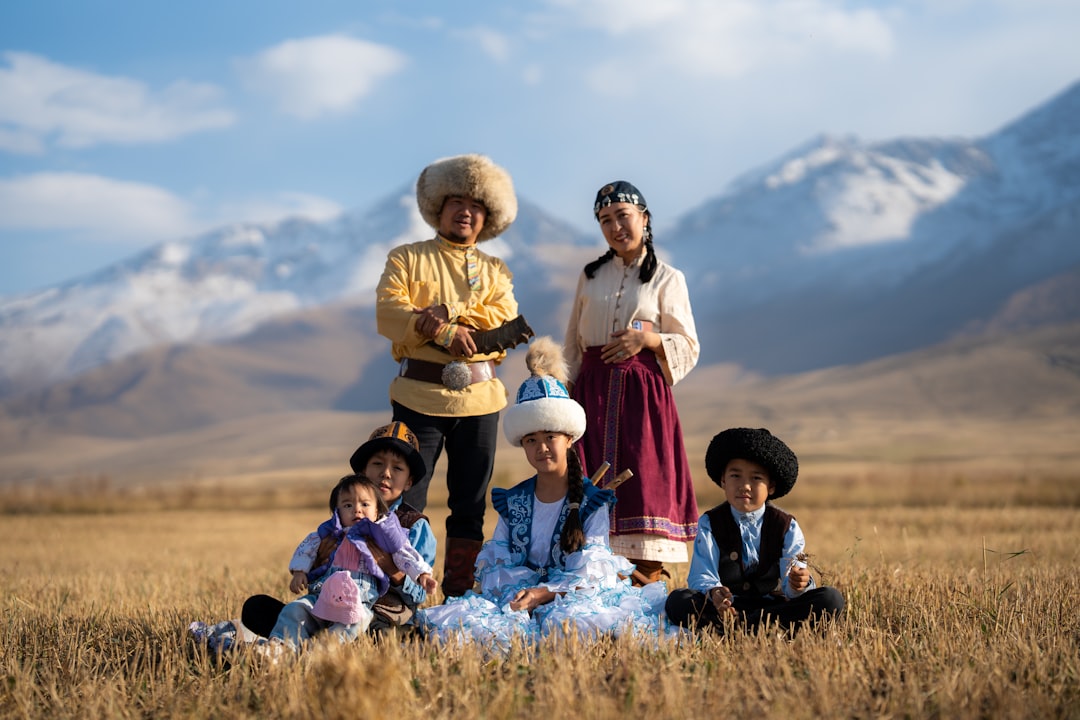 Children in traditional clothing pose in a field. traditional gathering, cultural clothing, mountain landscape, community celebration