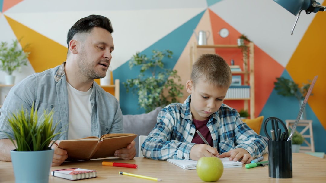 Father helps son with homework at a colorful desk. person teaching child, simple explanation concept, learning at home
