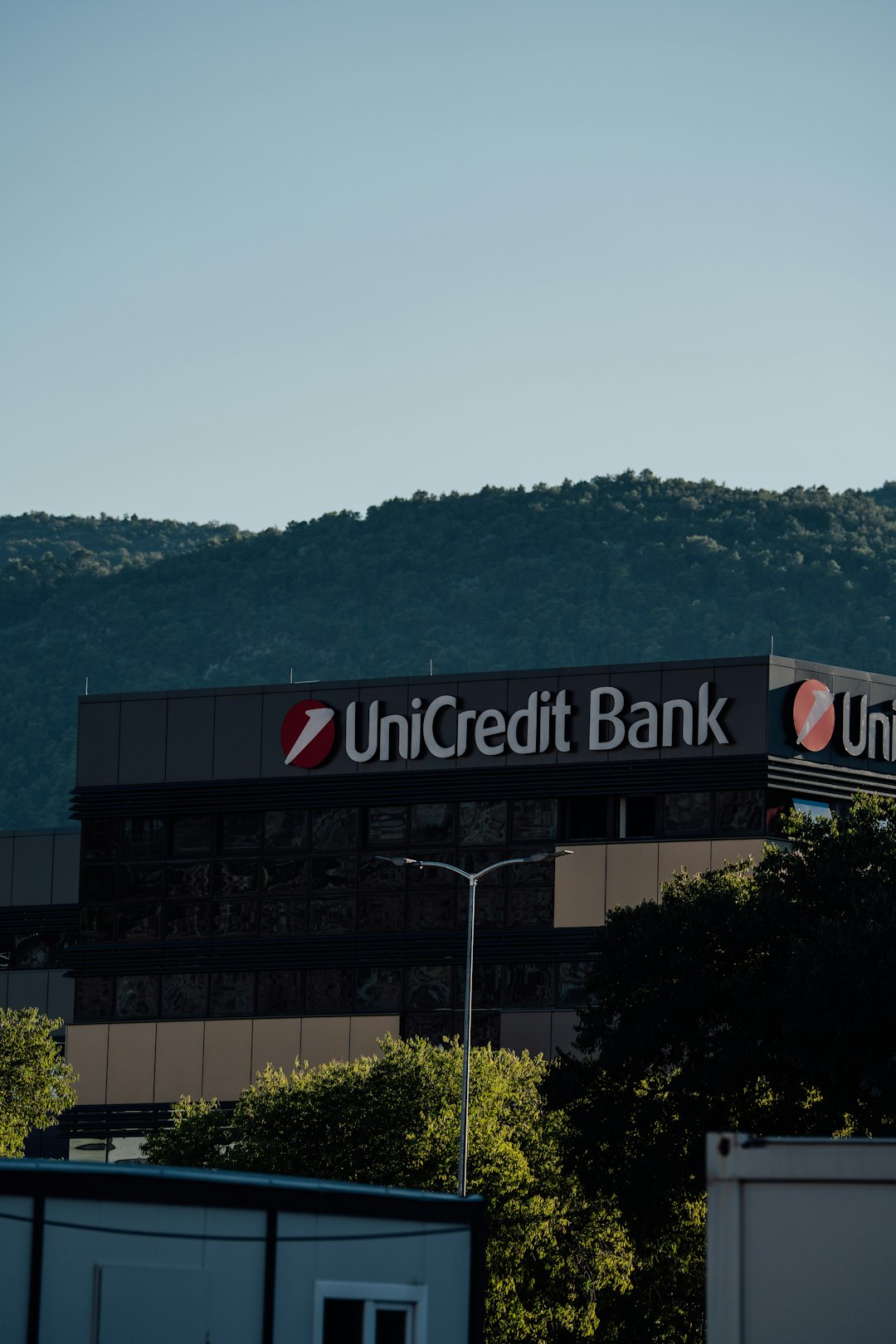 Unicredit bank building with trees and hills bank building exterior, atm machine, financial office interior