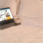 Laptop and coffee on a cozy, white bed. simple availability calendar, small bed and breakfast website, room booking calendar view