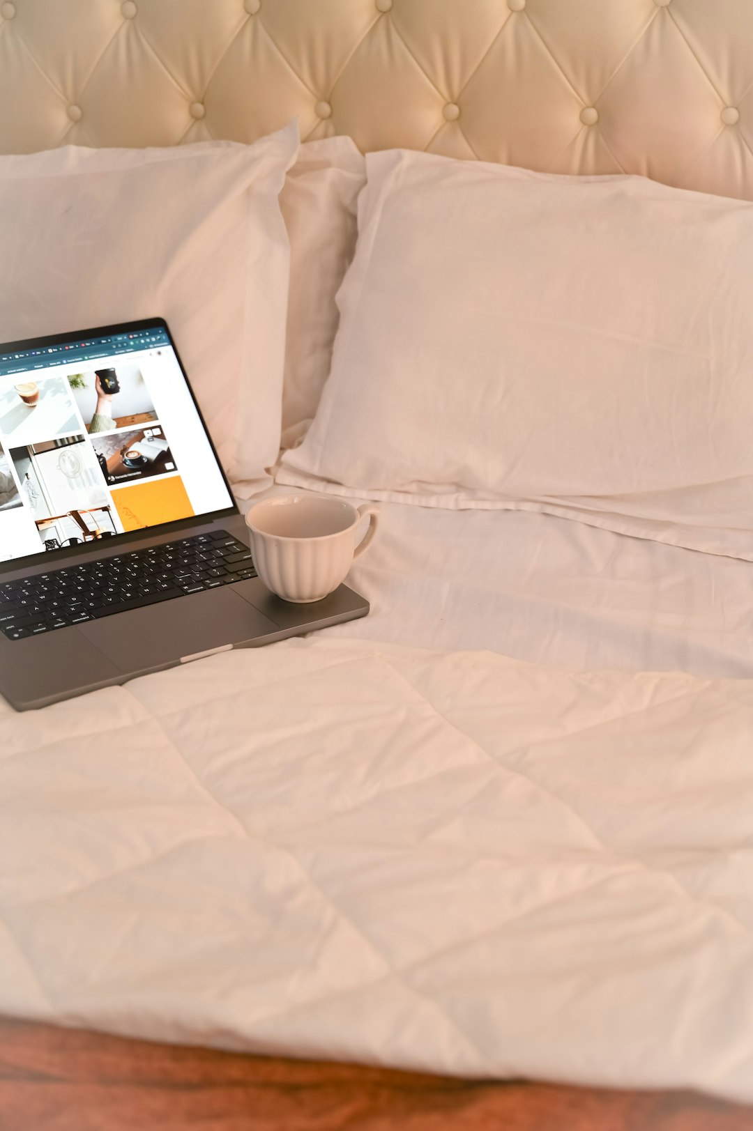Laptop and coffee on a cozy, white bed. simple availability calendar, small bed and breakfast website, room booking calendar view
