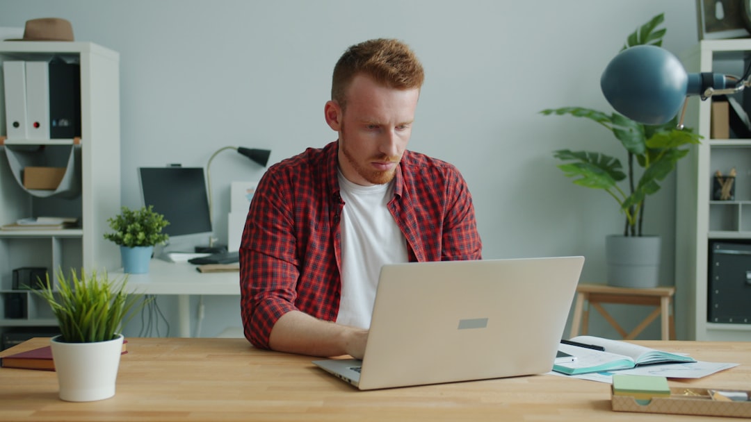 Man working on a laptop at a desk. plagiarism report screen, laptop writing desk, content editing software