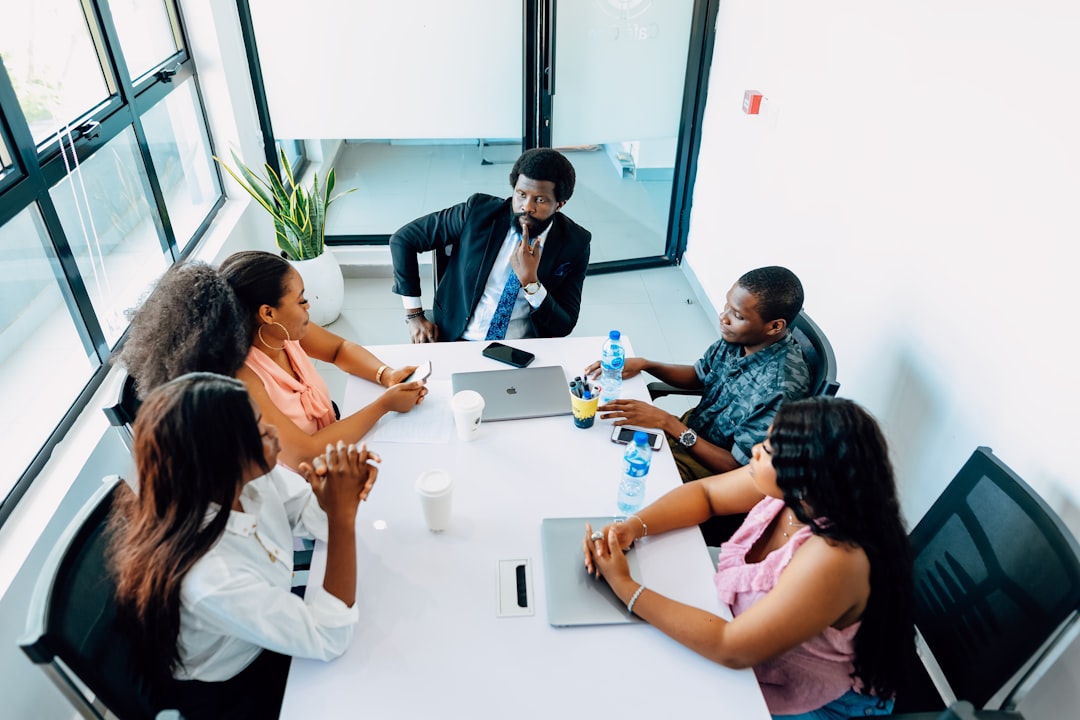 A group of people sitting around a white table business team reviewing analytics, digital contract management, collaborative workspace