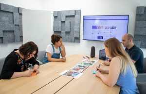 a group of people sitting around a wooden table project management dashboard, creative team collaboration, task approval workflow