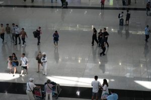 a group of people walking around a building person using laptop in airport, streaming video, travel suitcase nearby