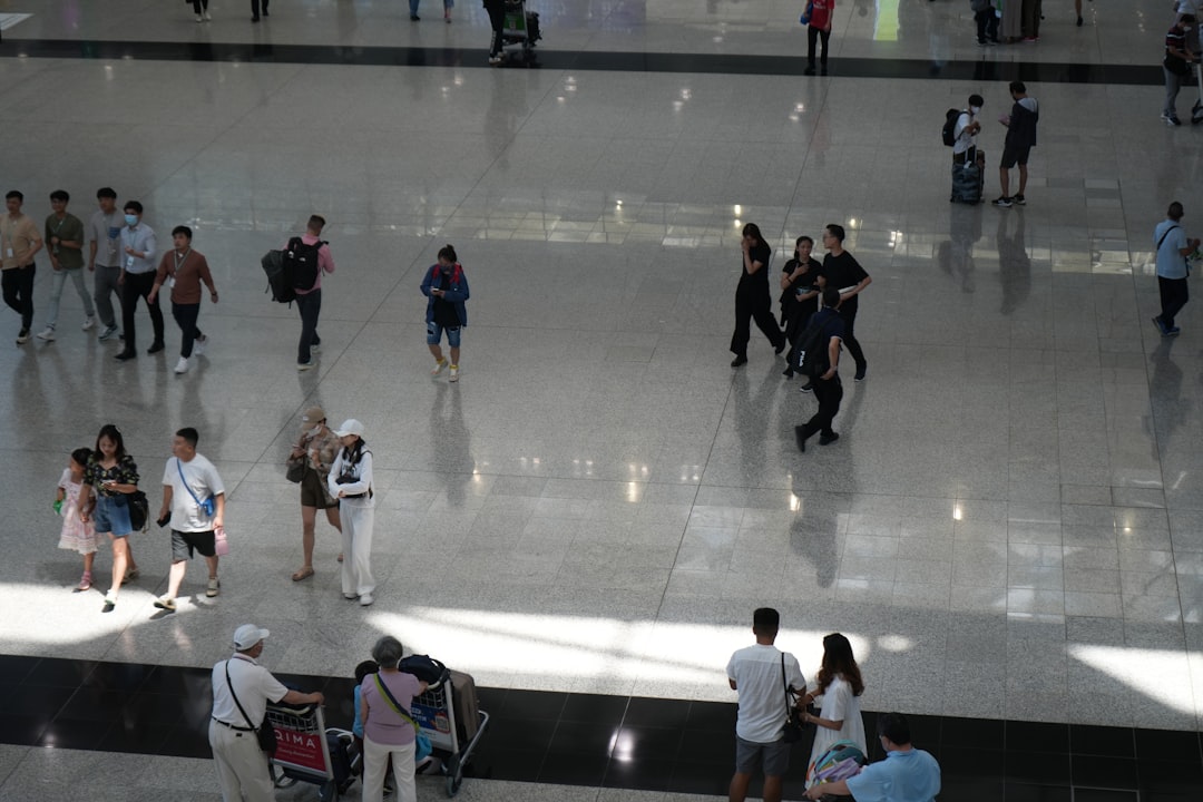a group of people walking around a building person using laptop in airport, streaming video, travel suitcase nearby