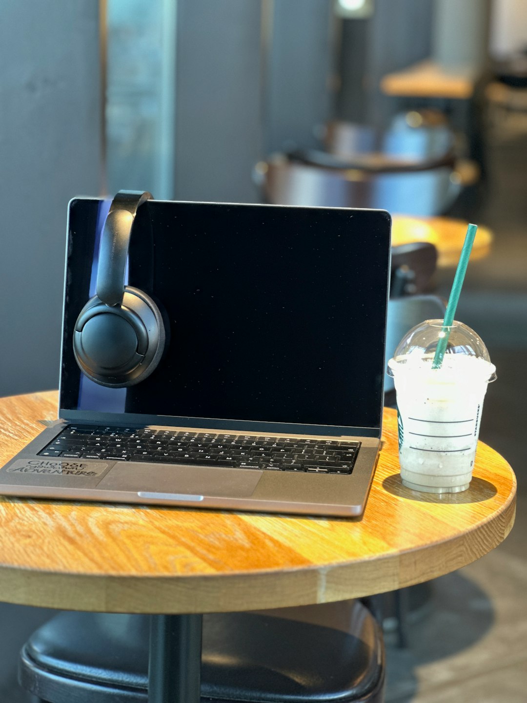a laptop computer sitting on top of a wooden table laptop with vpn interface open, coffee shop setting, public wifi concept