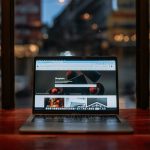 a laptop computer sitting on top of a wooden table wifi router on hotel desk, laptop streaming, smartphone connected