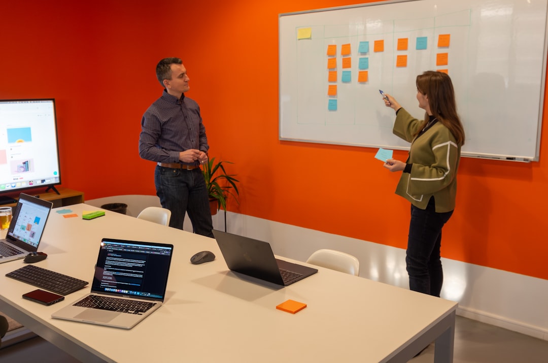 a man and a woman standing in front of a whiteboard team collaboration software developers brainstorming screens