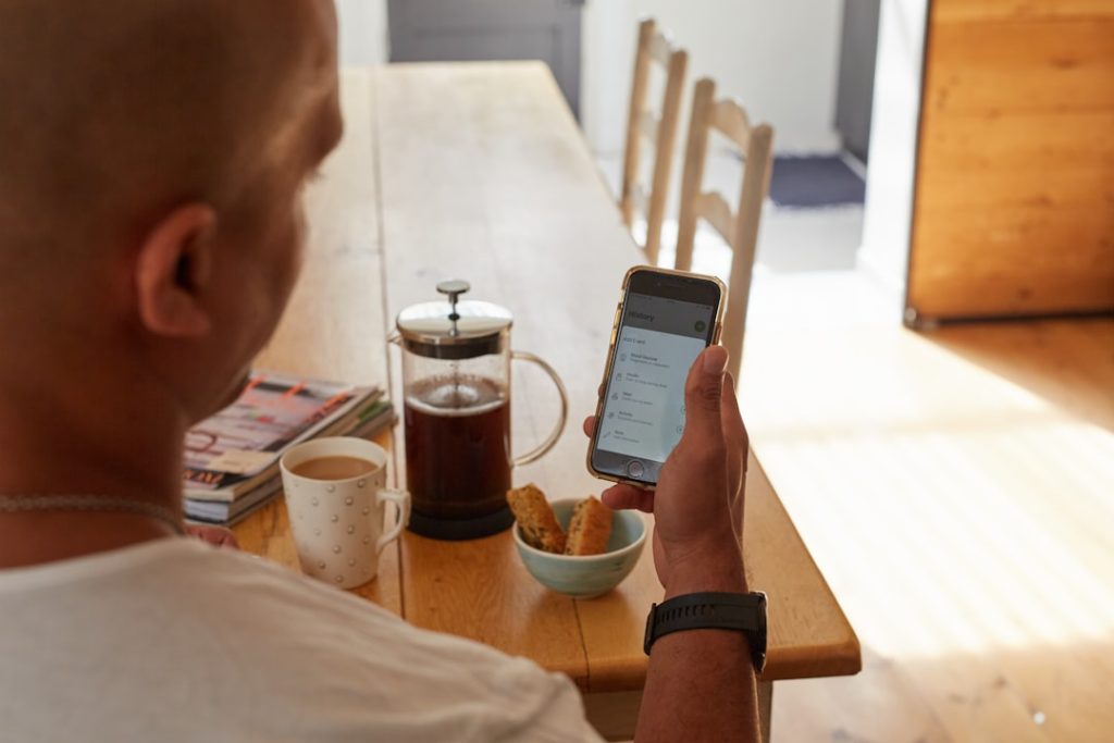 a man sitting at a table holding a smart phone customer support chat, mobile app interface, user engagement analytics