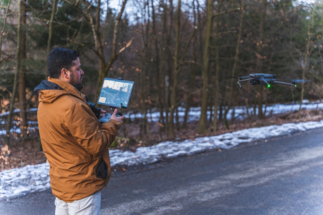 a man standing on the side of a road holding a laptop drone pilot reviewing tablet, flight analytics dashboard, team meeting with drone data