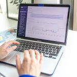 a person using a laptop computer on a desk ecommerce dashboard analytics charts laptop screen