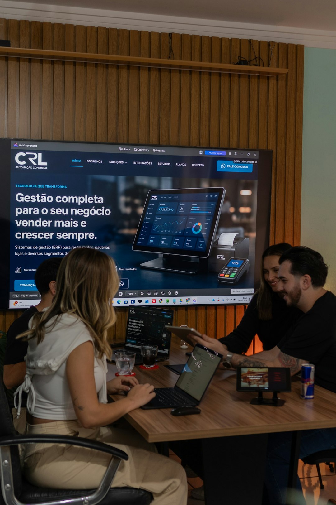 Colleagues collaborating around a table with a large screen display creative review dashboard, marketing team collaboration, online proofing interface