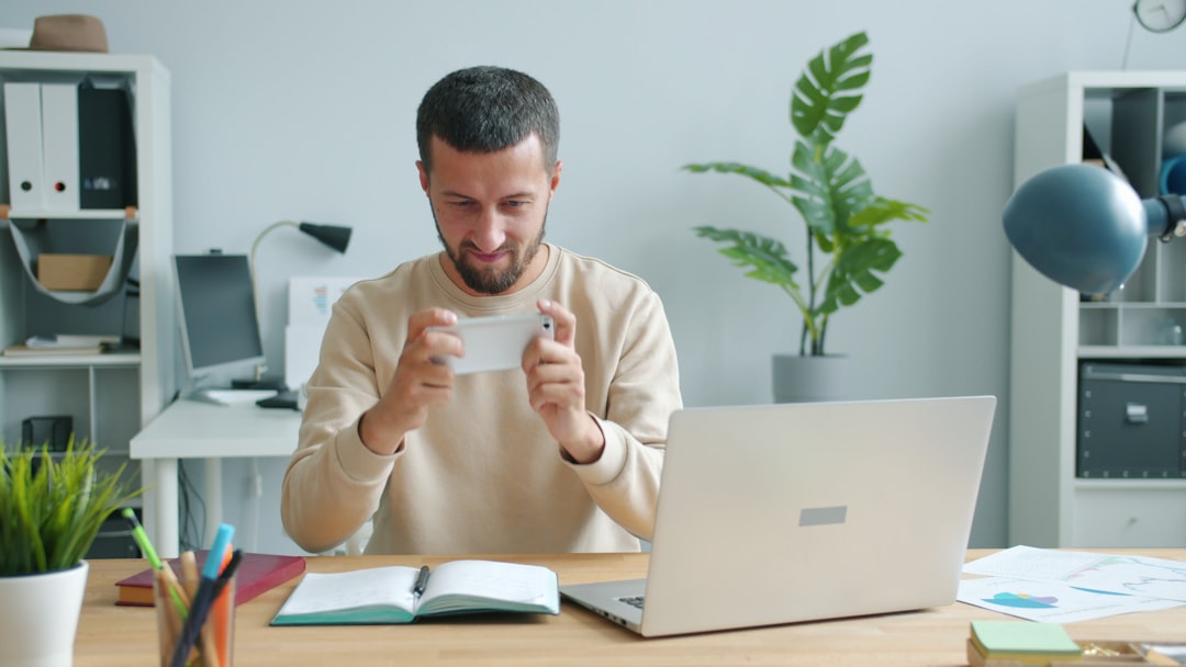 Man holding a card at a desk with laptop. customer reviews on laptop screen, five star rating, person reading feedback online
