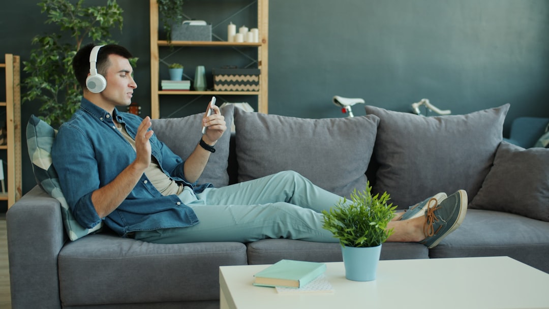 Man wearing headphones listens to music on couch. interior design software dashboard, planner 5d screen, virtual living room design, tablet design app