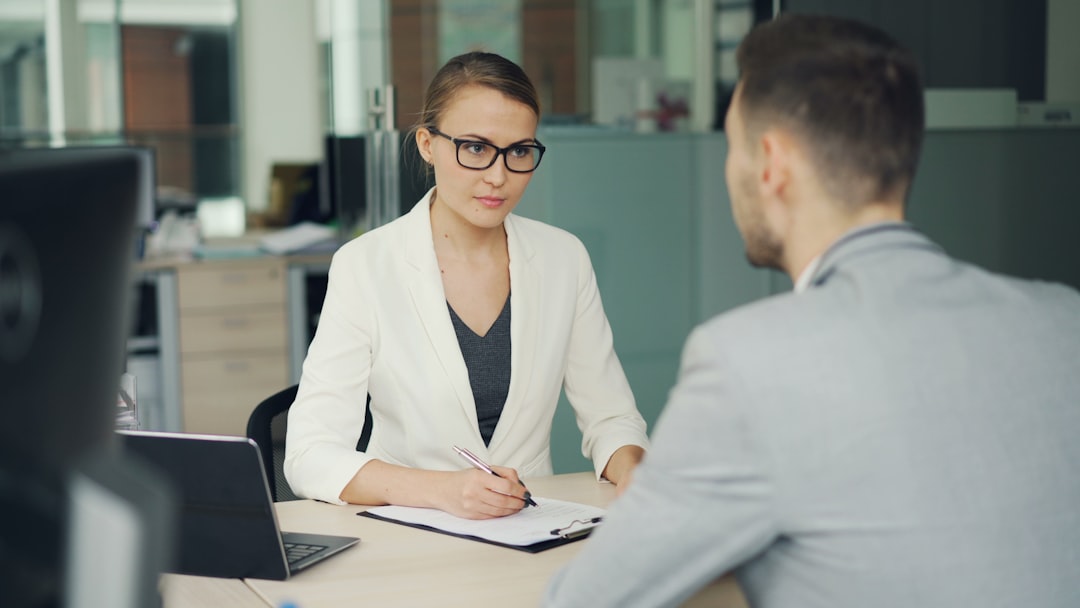 Woman in glasses interviews man at office desk. sales interview, hiring manager, confident candidate