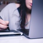 woman using drawing pad while sitting in front of laptop online notary video call, laptop signing documents, digital signature screen