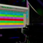 a close up of a computer monitor and keyboard live streaming gamer setup, colorful LED lights, streaming microphone and monitor