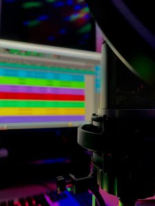 a close up of a computer monitor and keyboard live streaming gamer setup, colorful LED lights, streaming microphone and monitor