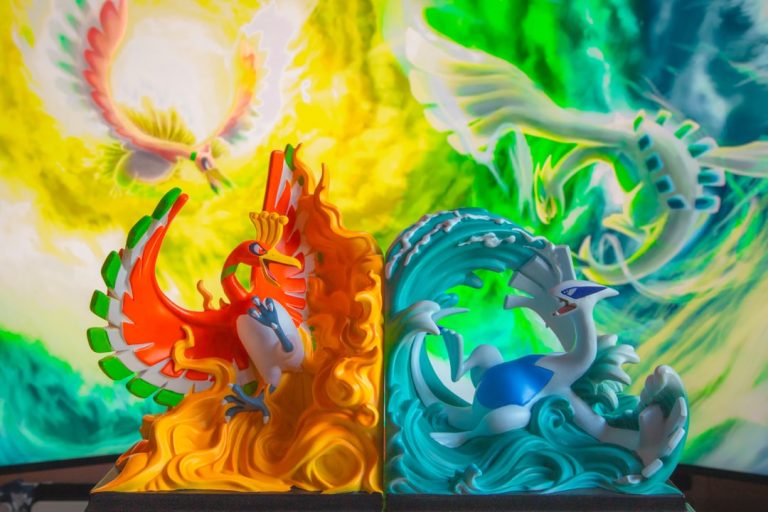 A couple of figurines sitting on top of a table dragon pokemon using powerful attack, glowing blue energy, battle arena minecraft