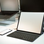 a desk with a laptop and a tablet business owner reviewing supplier options on laptop, ecommerce planning workspace, product sourcing strategy