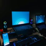 a desk with a laptop, monitor, keyboard and cell phone on it gaming pc setup, blue screen error, gamer desk