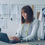 A fashion designer is working on her laptop. business owner reviewing supplier options on laptop, ecommerce planning workspace, product sourcing strategy
