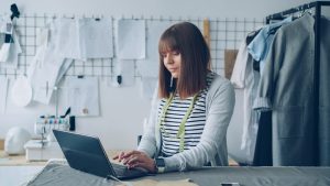 A fashion designer is working on her laptop. business owner reviewing supplier options on laptop, ecommerce planning workspace, product sourcing strategy