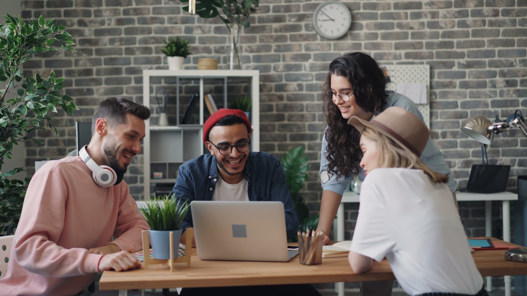 a group of people sitting around a table with a laptop team collaboration office, remote workers sharing files, business meeting laptop cloud software