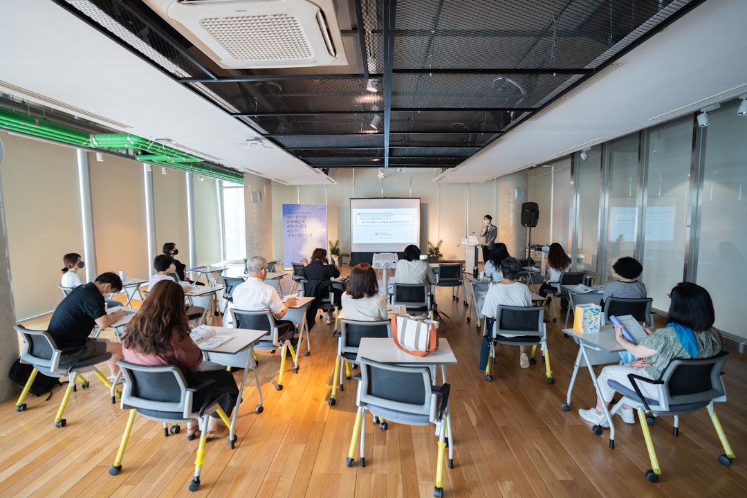a group of people sitting in a room with computers business team training session, digital learning system, office collaboration technology
