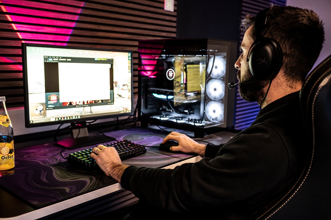 A man sitting in front of a computer with headphones on streamer wearing gaming glasses, RGB setup, headset and microphone, modern gaming room