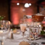 a person pouring wine into a glass on a table prosecco with appetizers, italian antipasto platter, sparkling wine brunch table