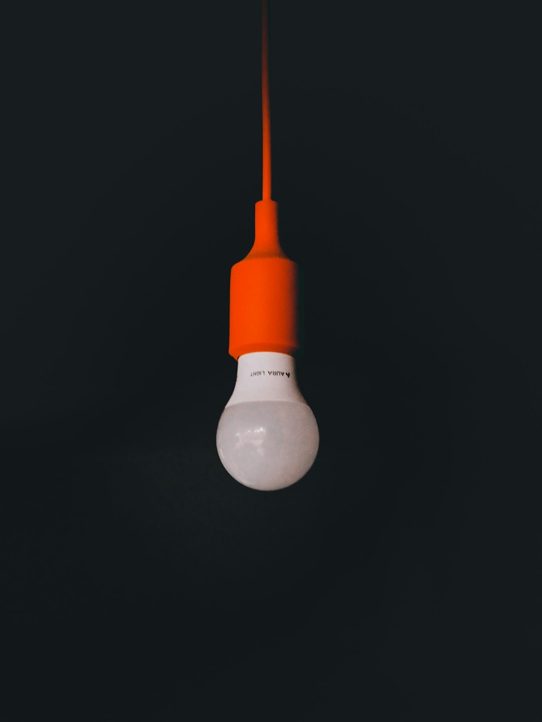 an orange light bulb hanging from a black ceiling lightbulb idea concept, simple analogy illustration, comparison visual