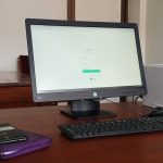 black computer monitor turned on beside black computer keyboard healthcare compliance dashboard, hipaa report screen, office computer setup