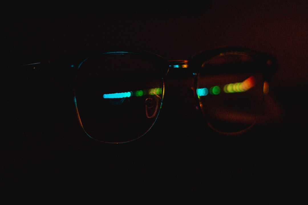 black framed eyeglasses on black surface close up gaming glasses lens reflection, high resolution screen, esports gameplay colors