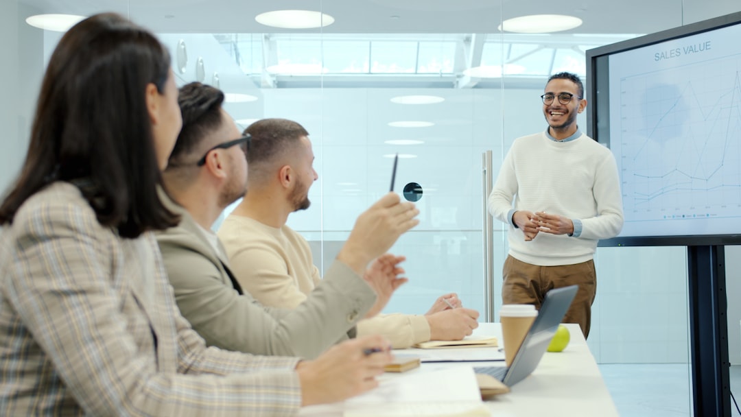 Man presenting to colleagues in a modern office setting business team training session, digital learning system, office collaboration technology