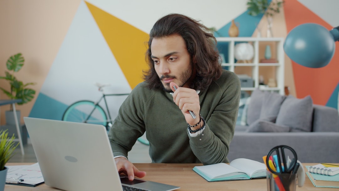 Man working on laptop in colorful modern office student studying laptop, step by step learning, cryptocurrency concept