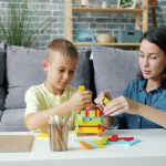 Mother and son building with colorful blocks person teaching child, simple explanation concept, learning at home