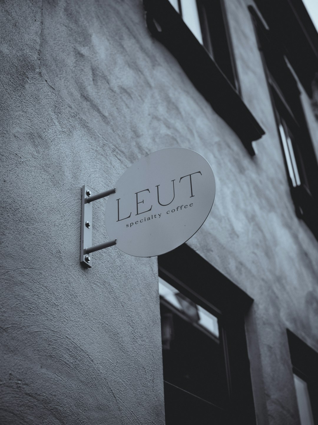 Round sign for leut specialty coffee on building minimal store sign, quiet luxury, modern branding, simple facade