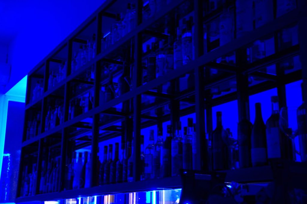 Shelves of bottles glow under blue light. cloud data center servers racks blue lighting