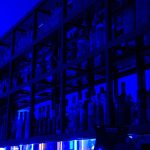 Shelves of bottles glow under blue light. cloud data center servers racks blue lighting