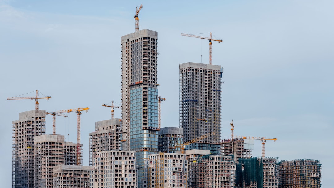 Skyscrapers under construction with cranes against sky. construction team meeting, laptop with building plans, high rise construction site